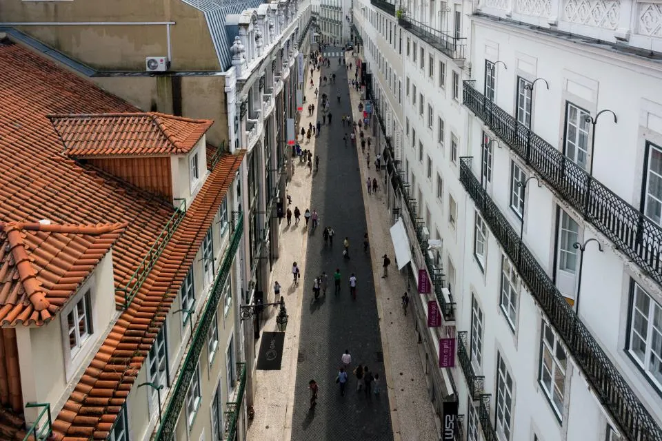 Rua pedonal de Lisboa vista de cima, com telhados de telha e prédios de fachada clara